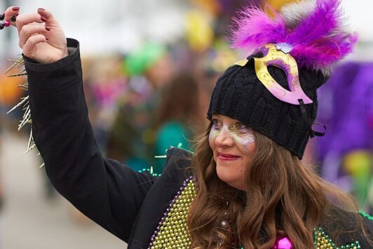 A woman throws beads during Mardi Gras in St. Louis.