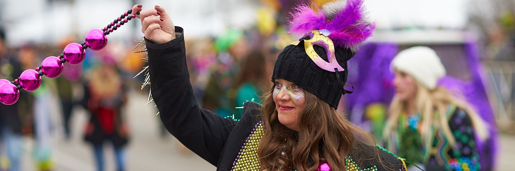 A woman throws beads during Mardi Gras in St. Louis.