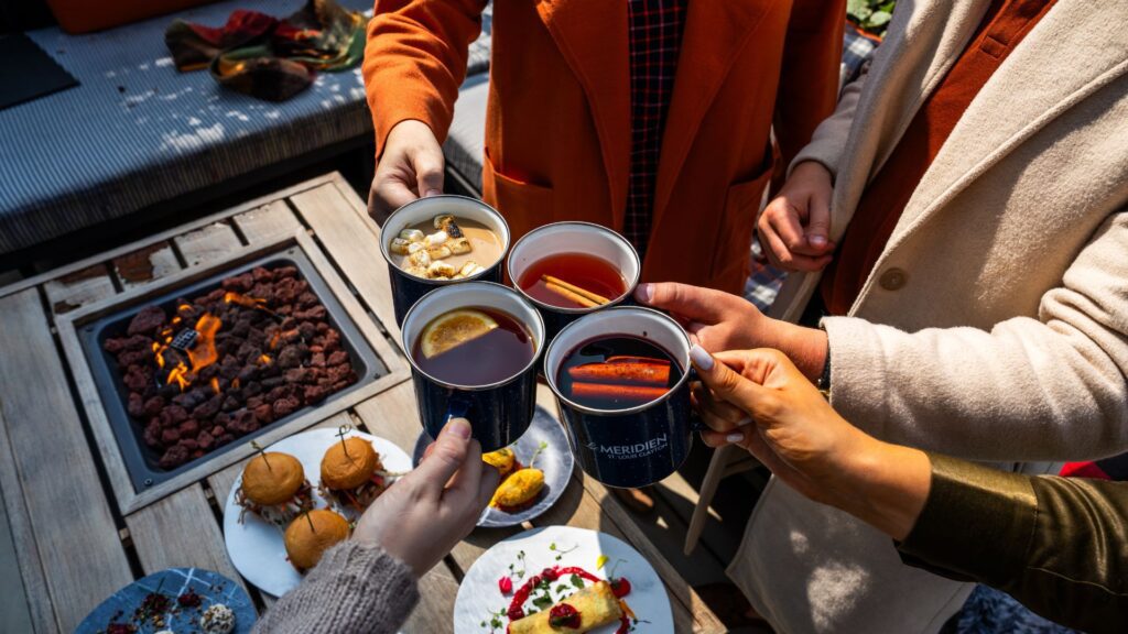 People cheers with warm drinks at The Chalet, a holiday pop-up bar at Le Méridien St. Louis Clayton.