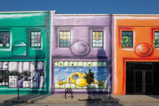 Part of The Walls Off Washington, Kranzbergville, a mural by Kenny Scharf, features four brightly colored buildings that resemble animated faces.