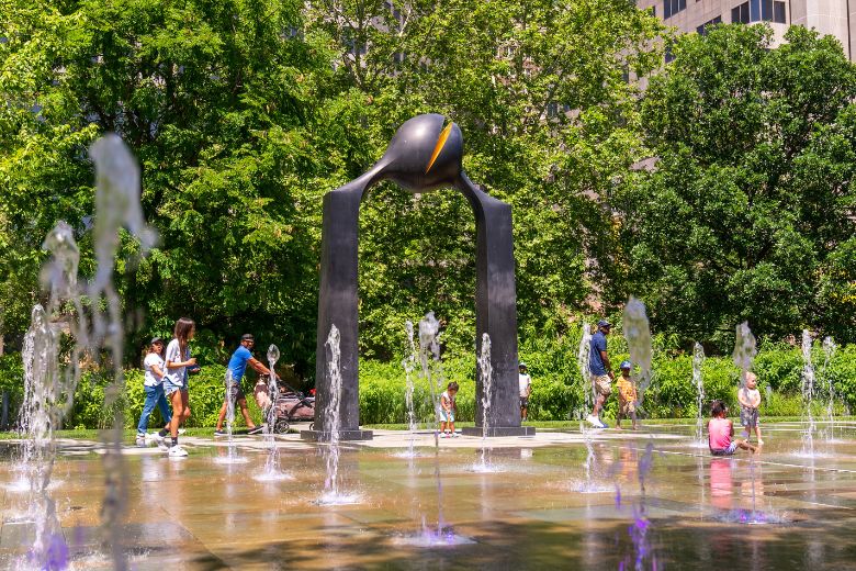 A family plays in the dancing fountains at Citygarden.