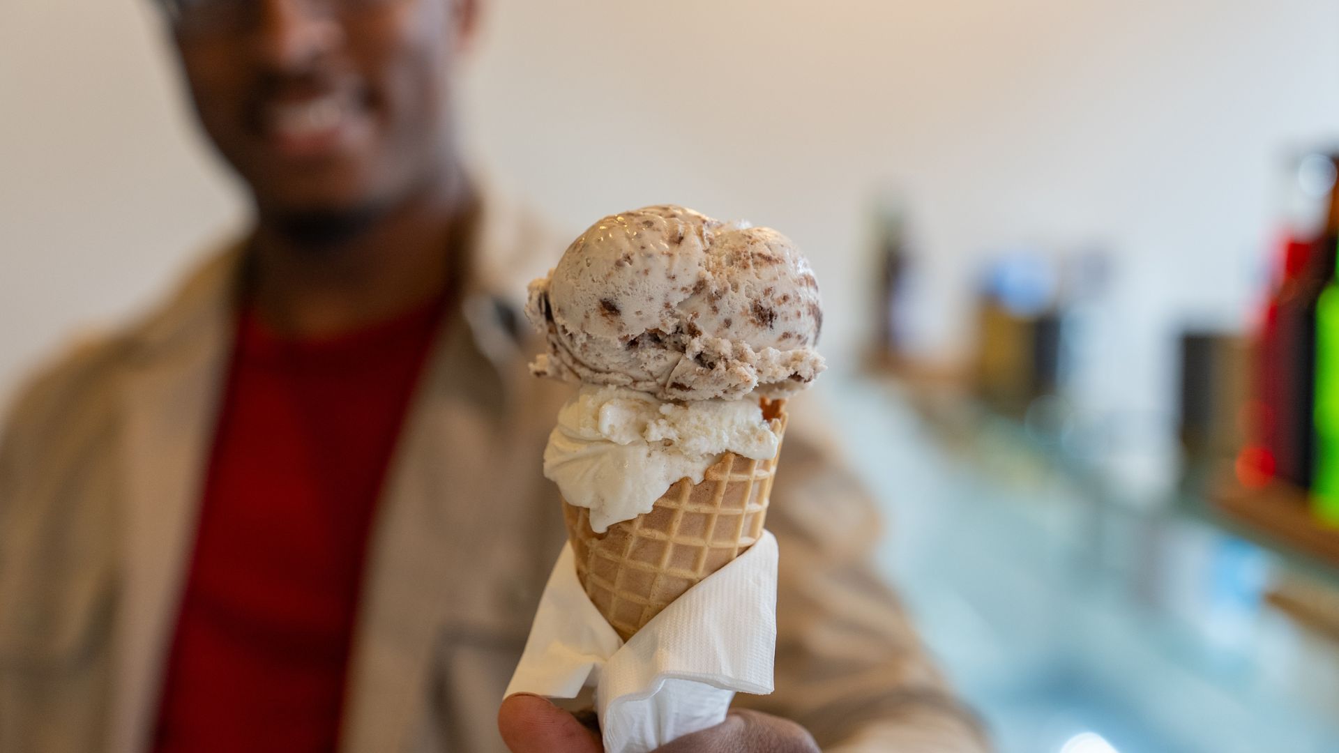 The owner of A Spoonful of Sugar hands an ice cream cone to a customer.