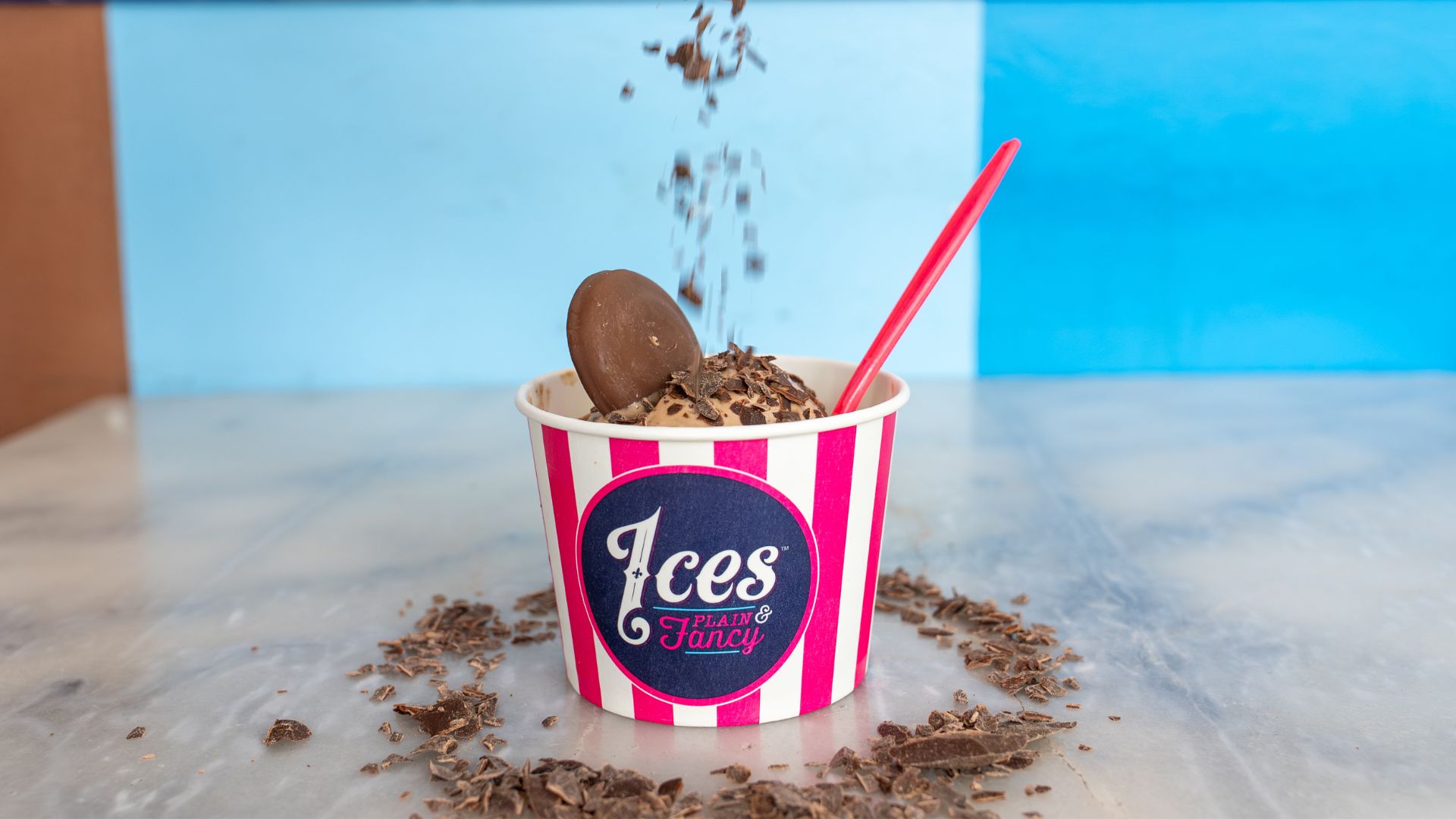 Chocolate garnishes are sprinkled onto a cup of ice cream at Ices Plain & Fancy.