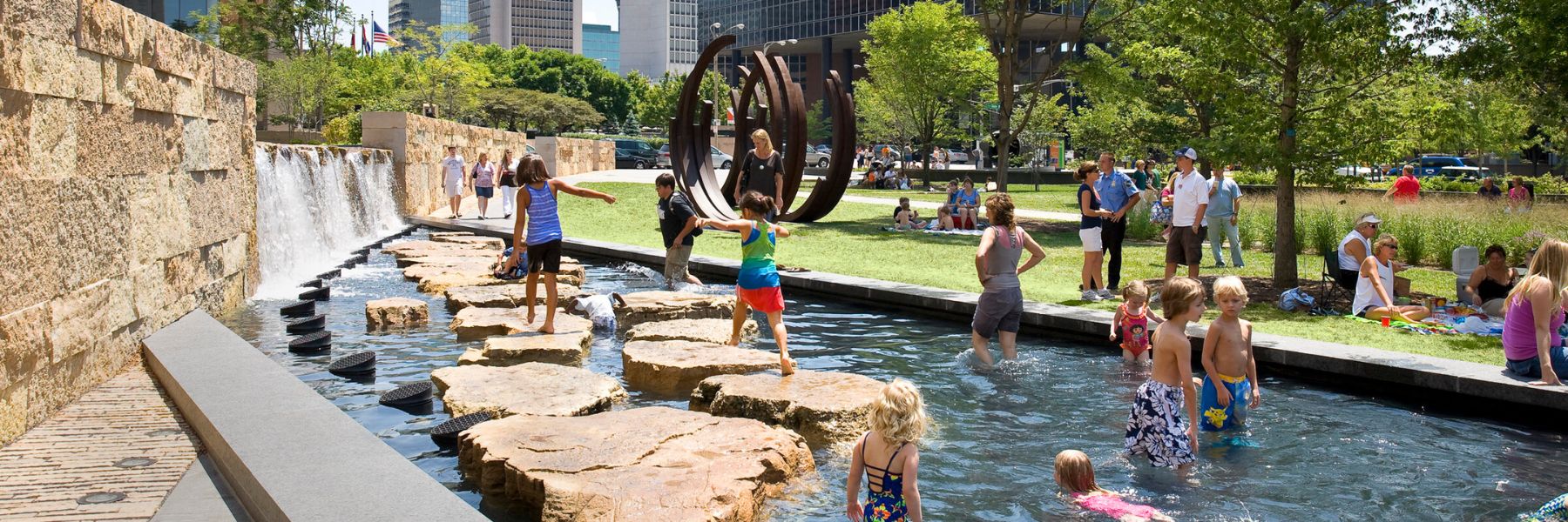 Families play in the water features at Citygarden to keep cool in St. Louis.