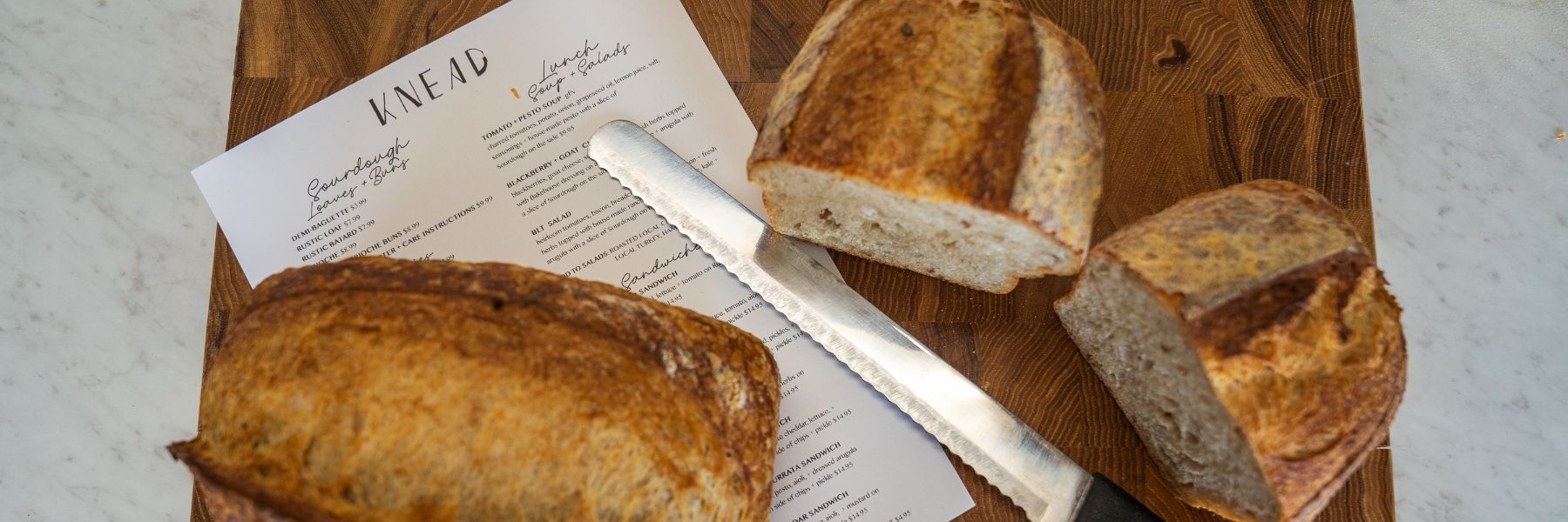 Rustic sourdough bread sits on a menu at Knead Bakehouse + Provisions.