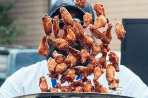 A St. Louis restaurant owner tosses wings in sauce.