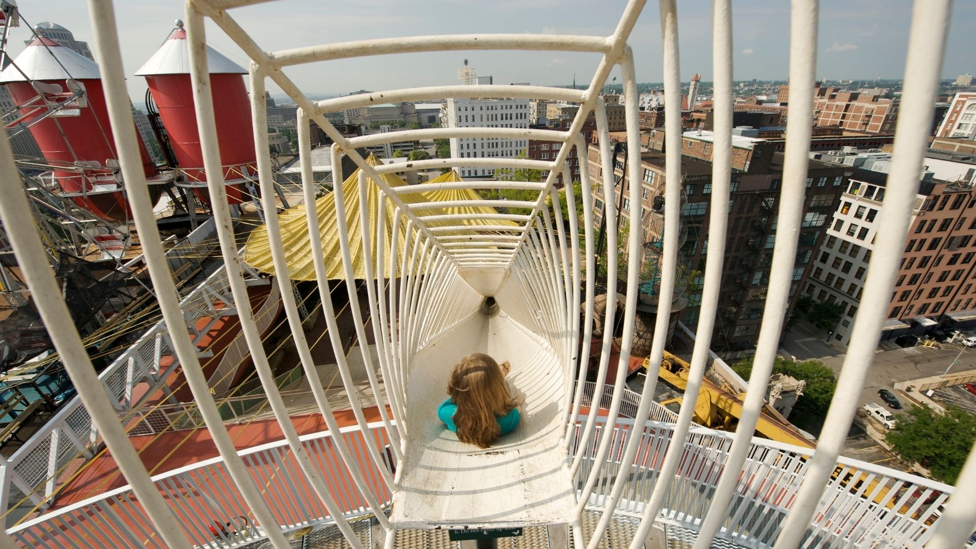A young girl starts down a slide on the roof of City Museum.