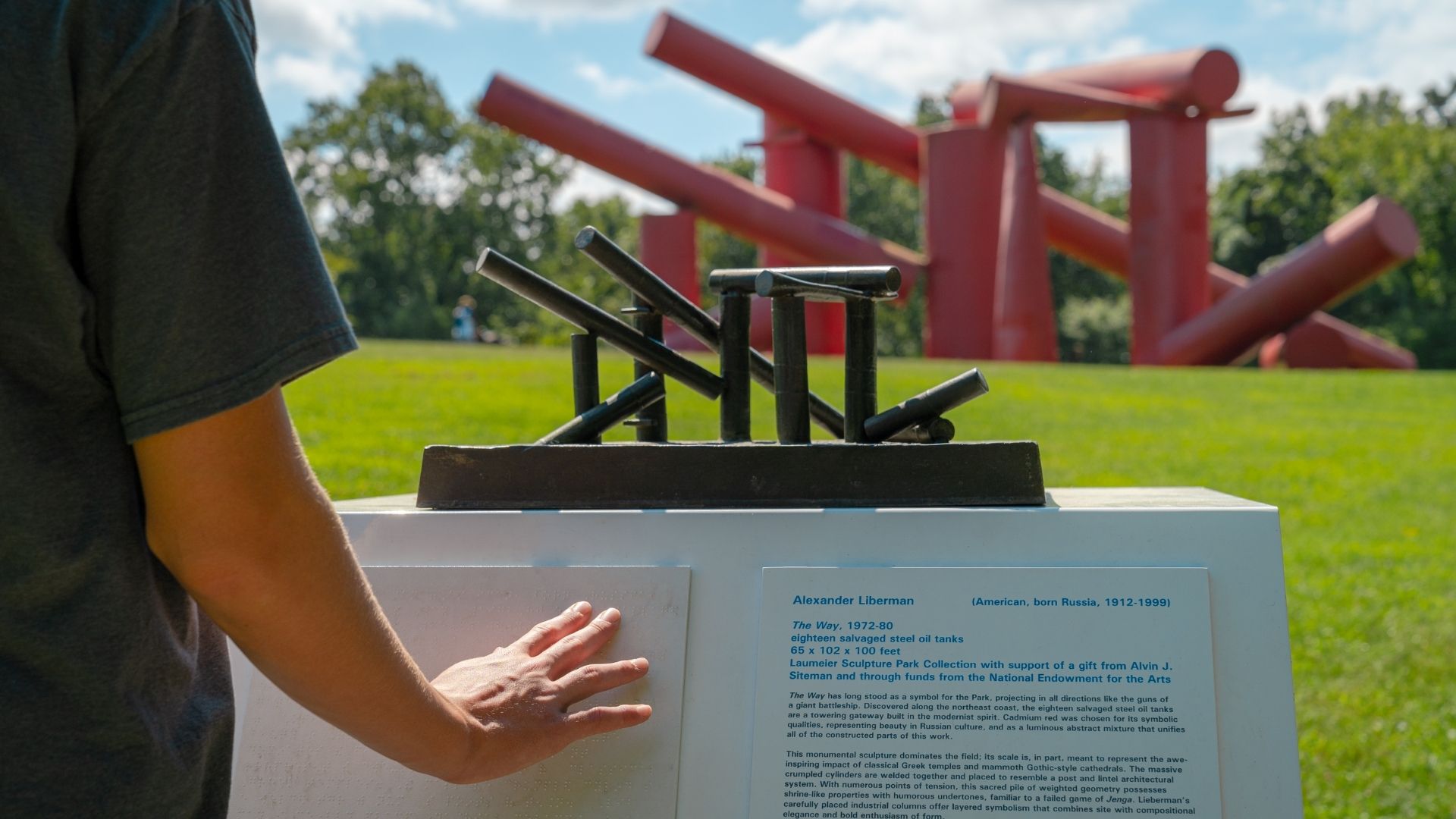 A visitor reads a sign in braille at Laumeier Sculpture Park.