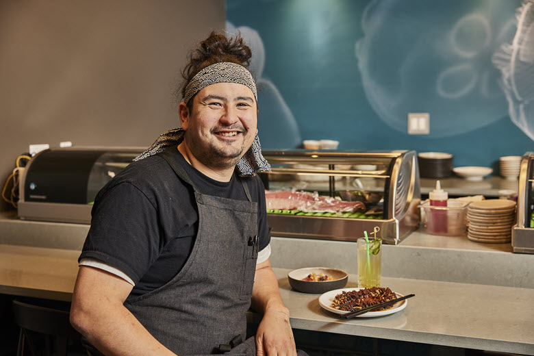 Nick Bognar poses at the sushi bar of his restaurant Sado.