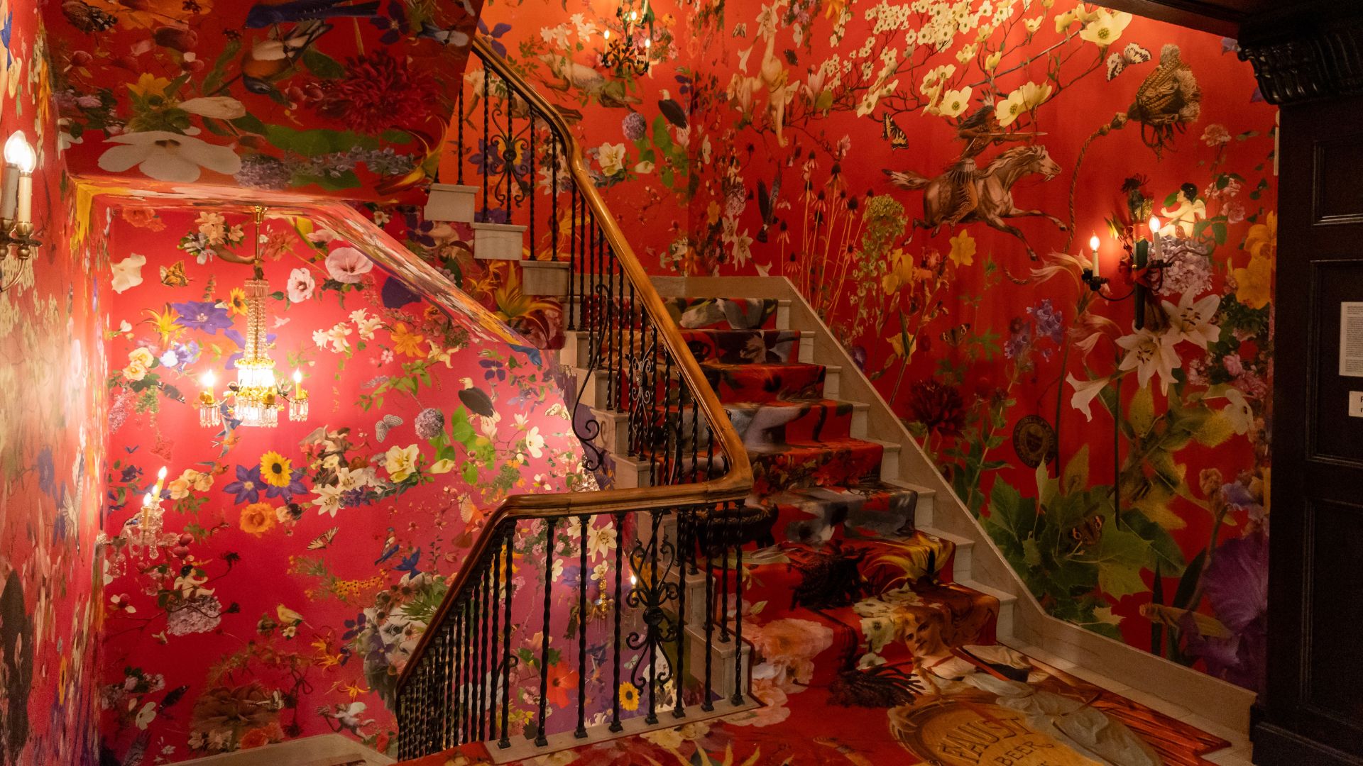 This grand staircase features vibrant, colorful wallpaper and carpet designed by Fallen Fruit.