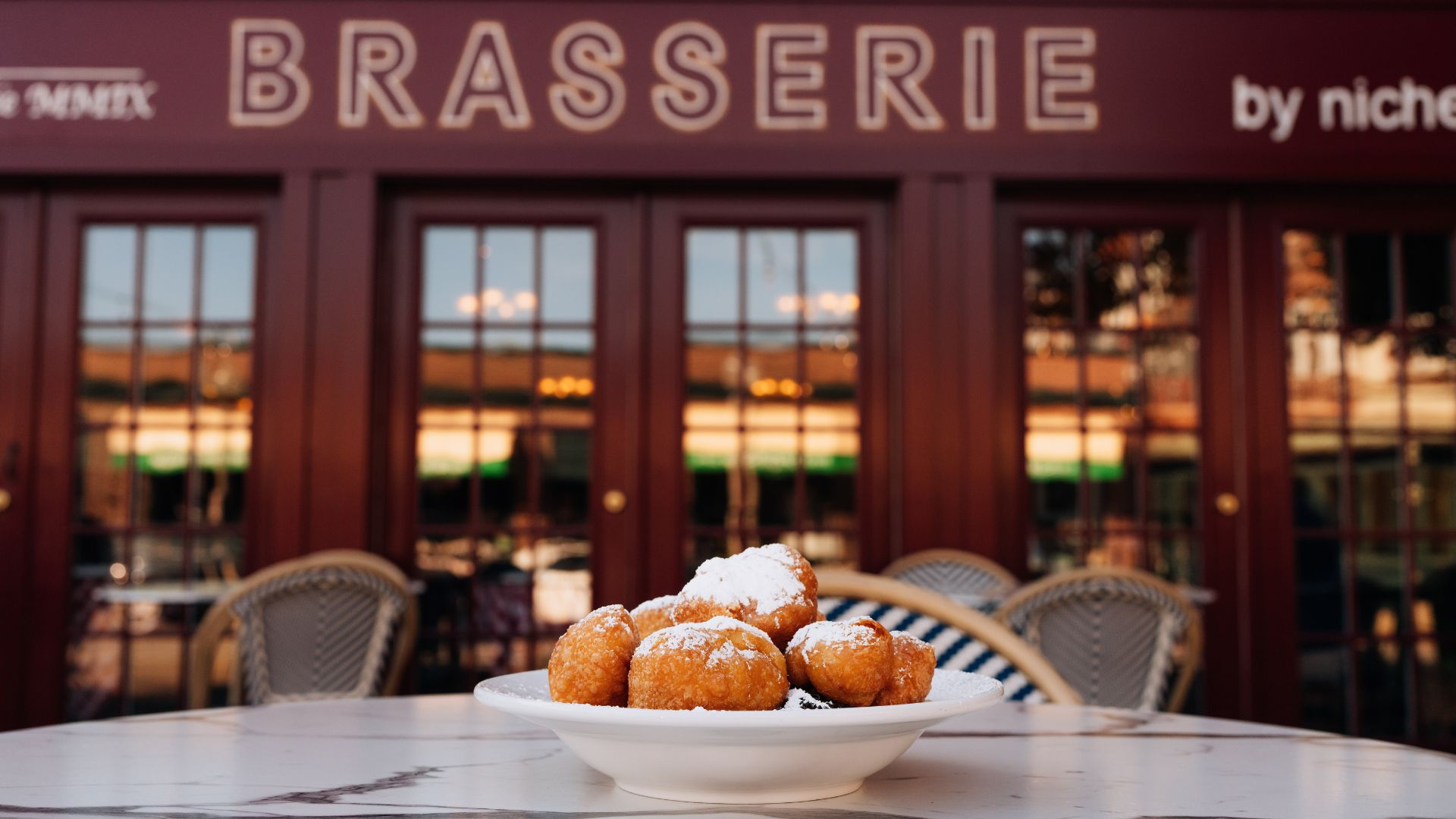 Beignets sit on a table on the patio at Brasserie by Niche.