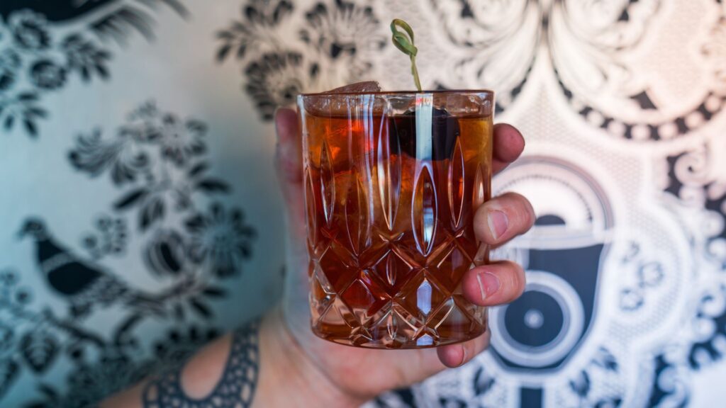 Someone toasts with a whiskey cocktail at Small Batch in St. Louis.