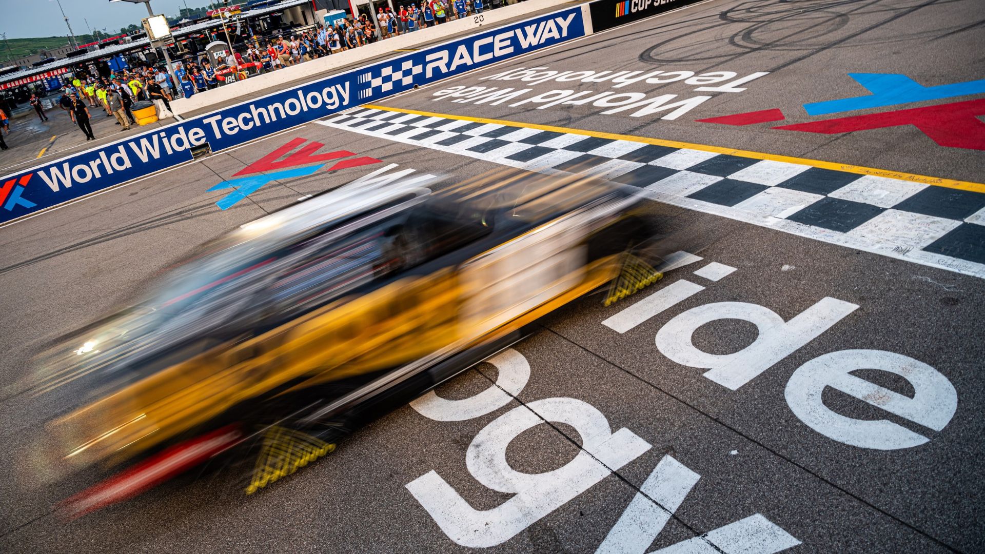 A car races across the finish line during a NASCAR Cup Series race at World Wide Technology Raceway.