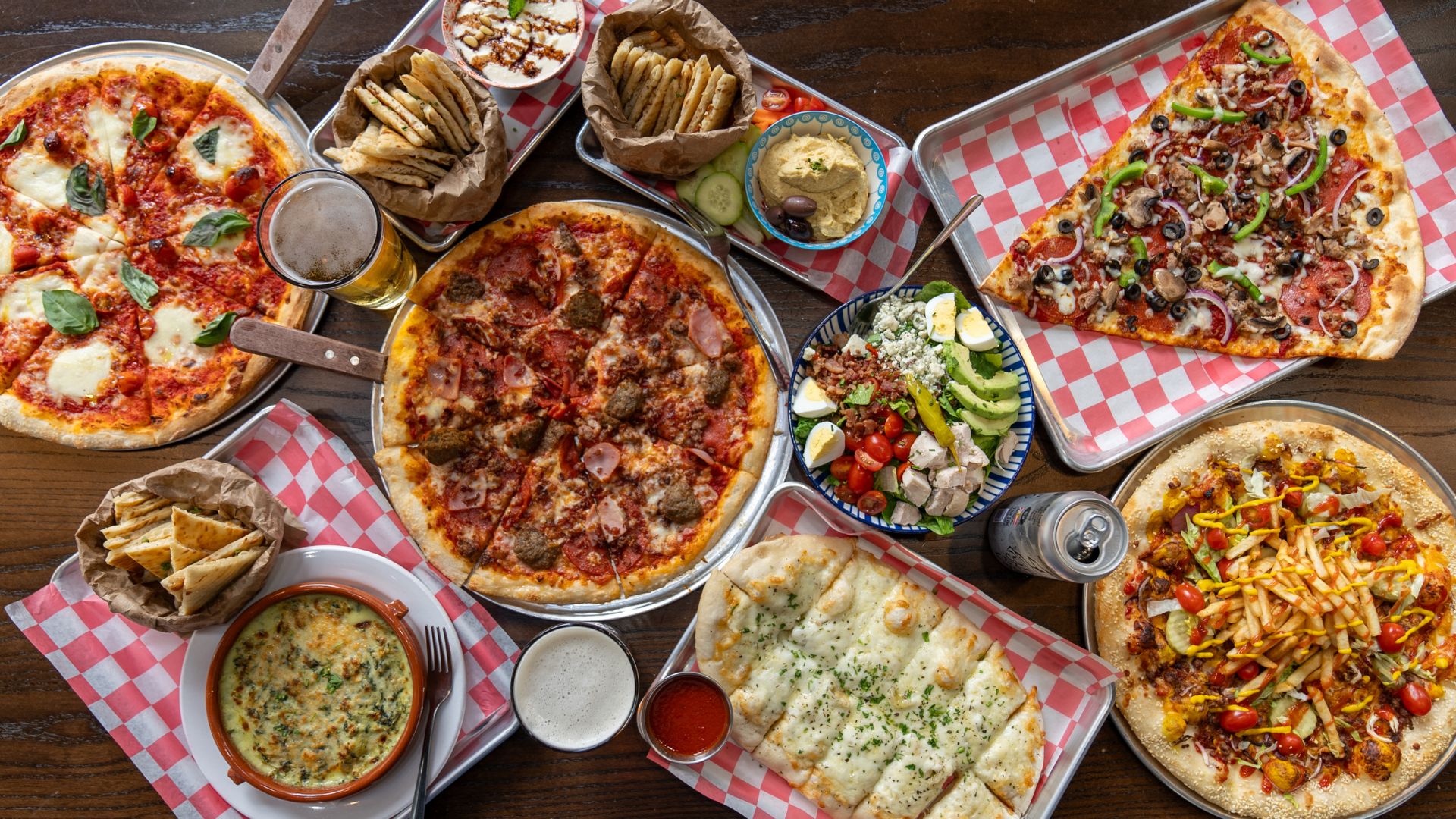 A spread at Hot Pizza Cold Beer includes pizza, dips, salads and beer.