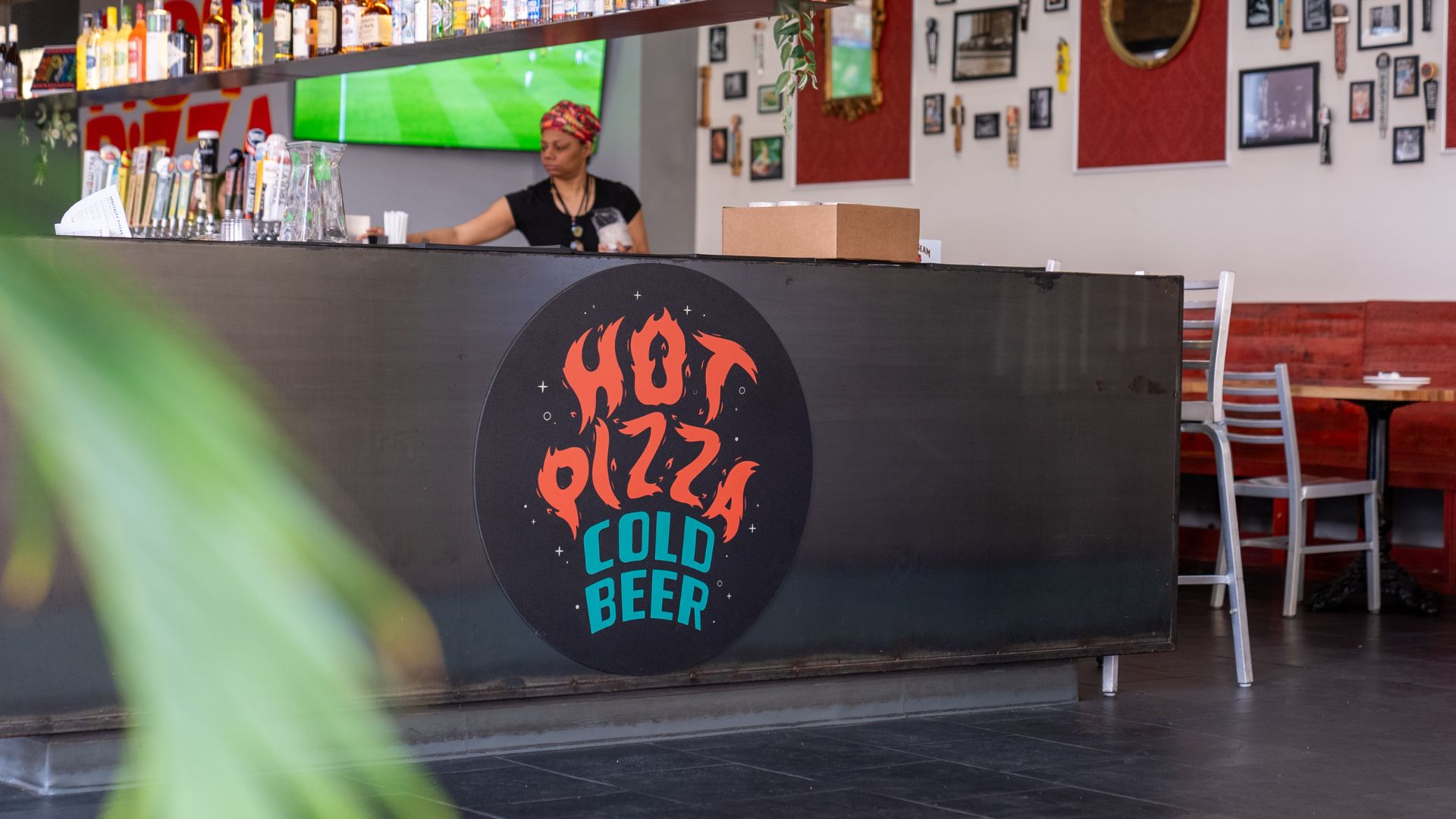 A woman serves beer behind the bar at Hot Pizza Cold Beer.