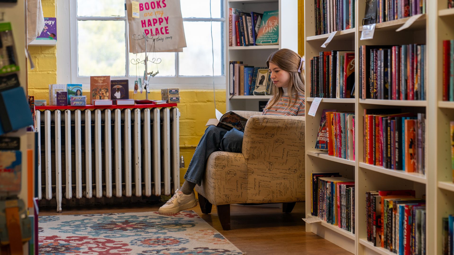 A young woman reads in a corner of a bookstore.