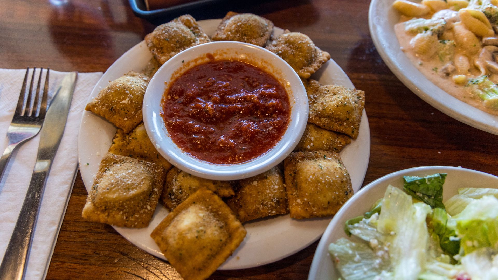 A spread from The Pasta House Co. features toasted ravioli, salad and pasta con broccoli.