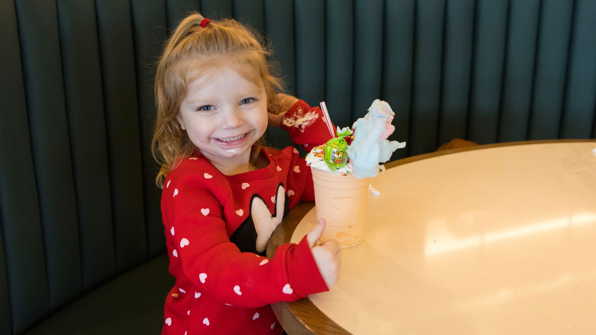 A little girl smiles with her over-the-top milkshake at The Soda Fountain.