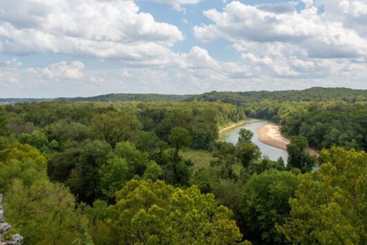Hikers perch on a limestone bluff overlooking a river at Castlewood State Park.