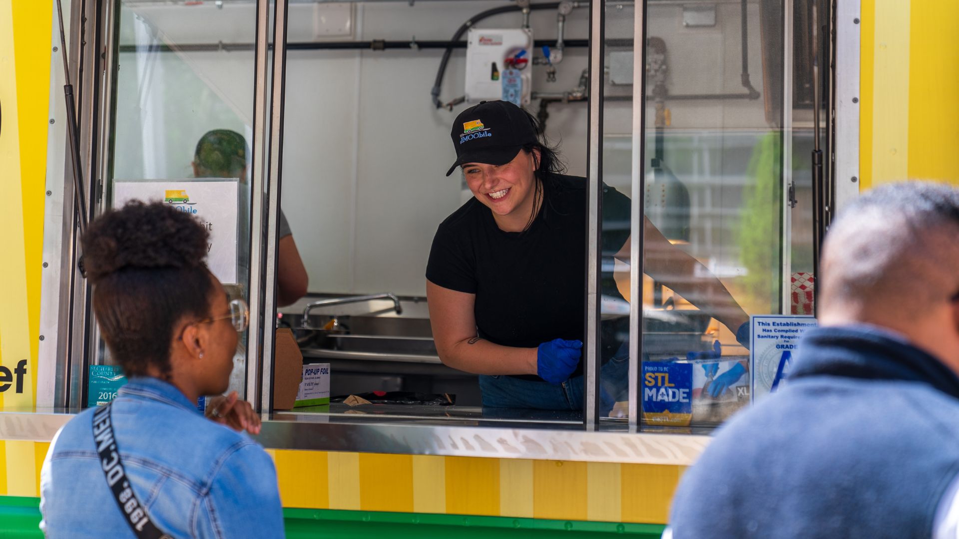 A smiling worker serves smash burgers from The MOObile food truck.