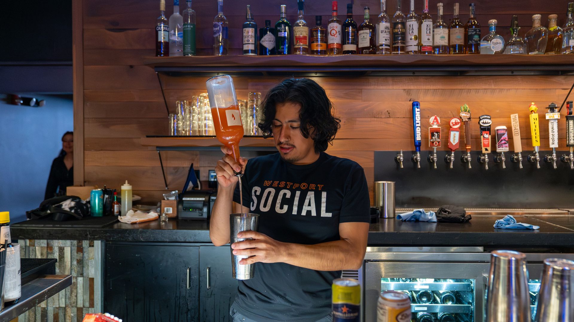 Oliver Tizpantizi-Serrano pours a drink behind the bar at Westport Social in St. Louis.