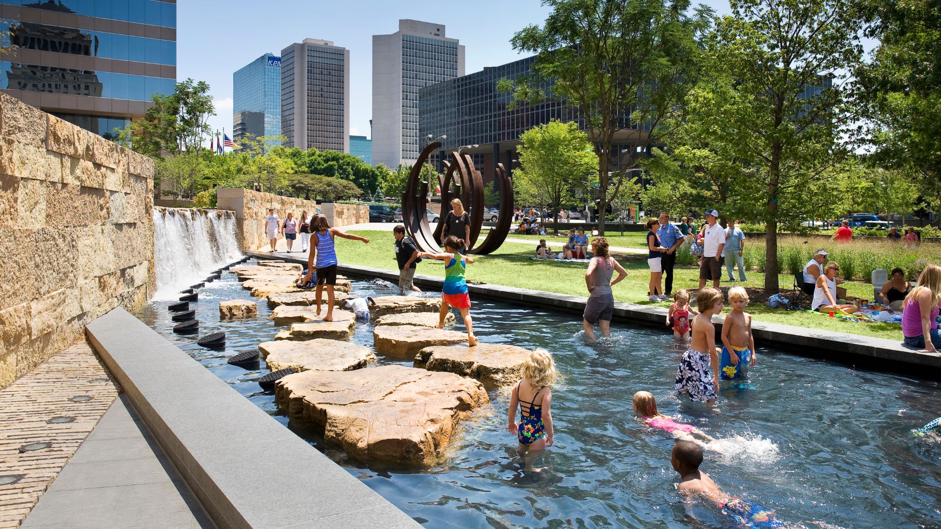 Families play in the water features at Citygarden to keep cool in St. Louis.