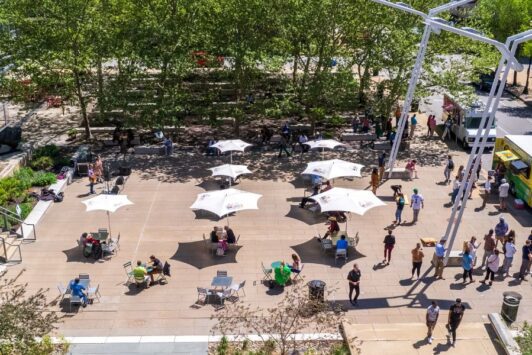 People enjoy lunch in a sunny plaza in downtown St. Louis.