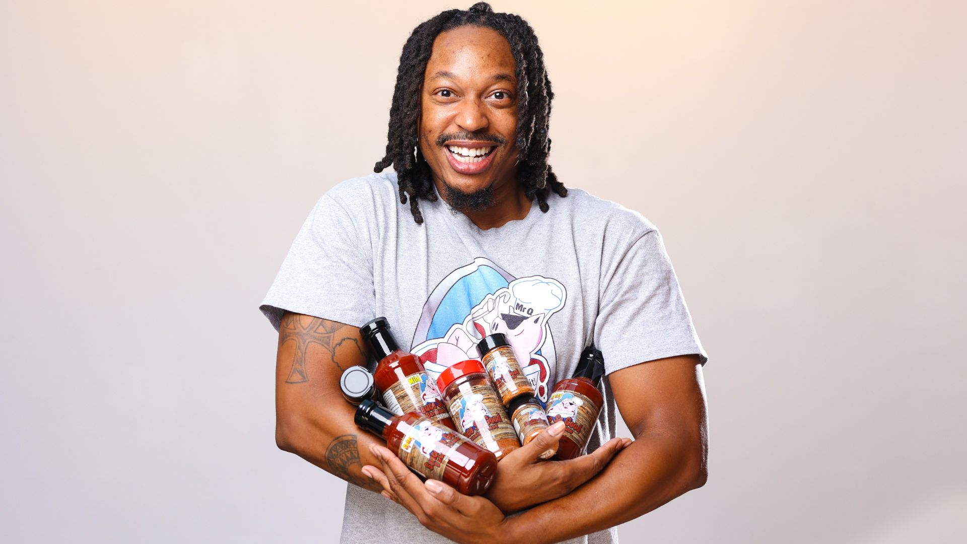 Keyon Watkins, owner of Sauce So Good, holds an armful of barbecue sauces and rubs.