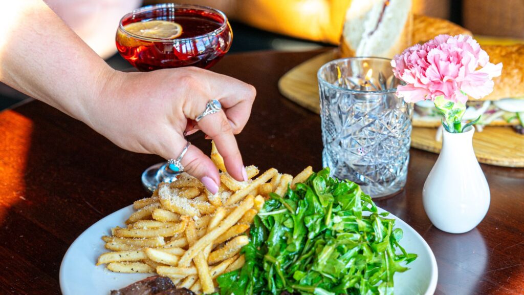 A hand reaches for a plate of fries at POP in Lafayette Square.