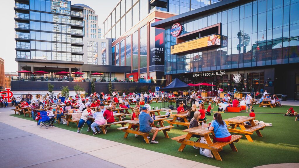 People eat and drink on picnic benches in the middle of Ballpark Village.