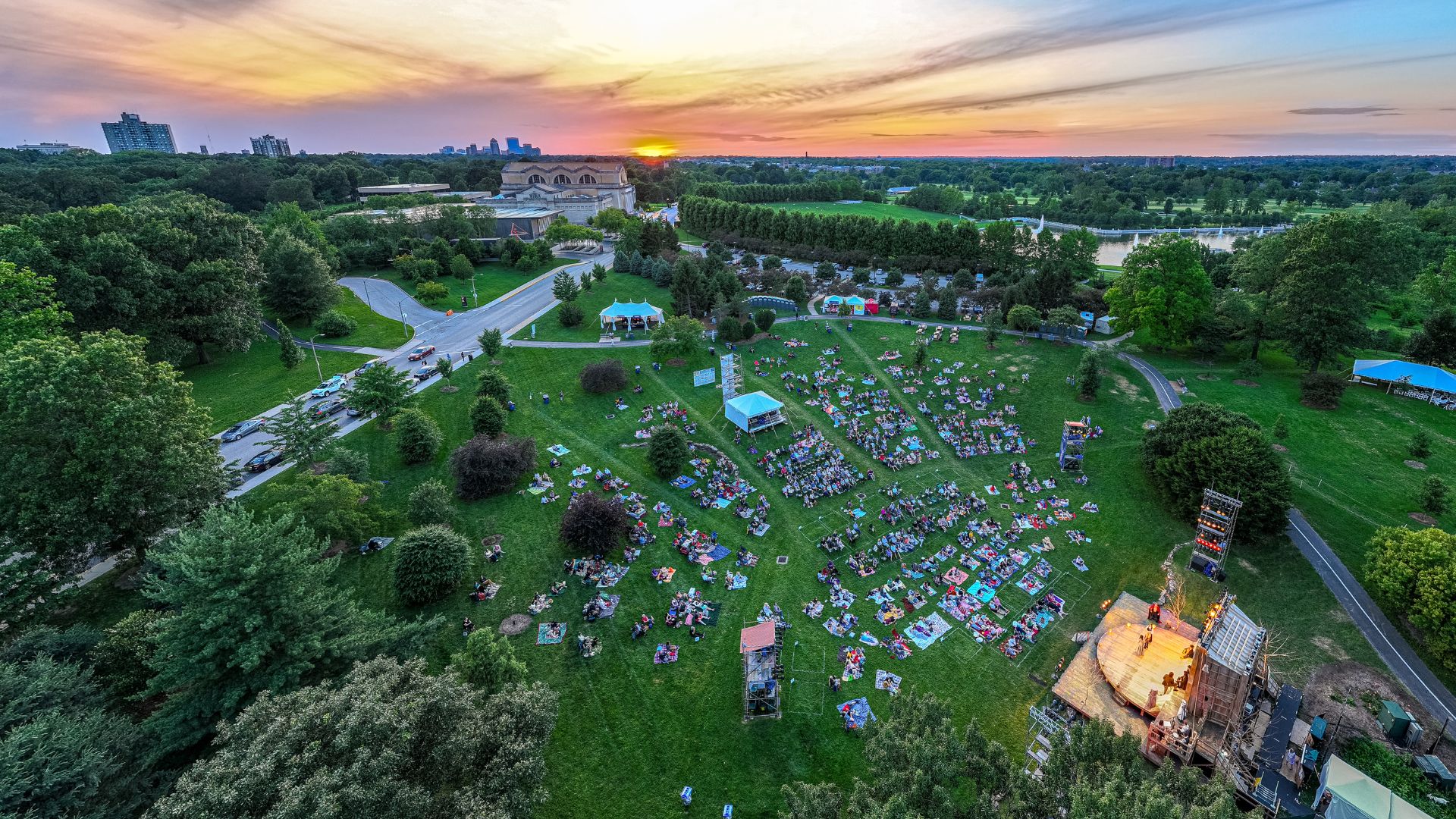 A drone shot captures the setting sun over the St. Louis Shakespeare Festival in Forest Park.