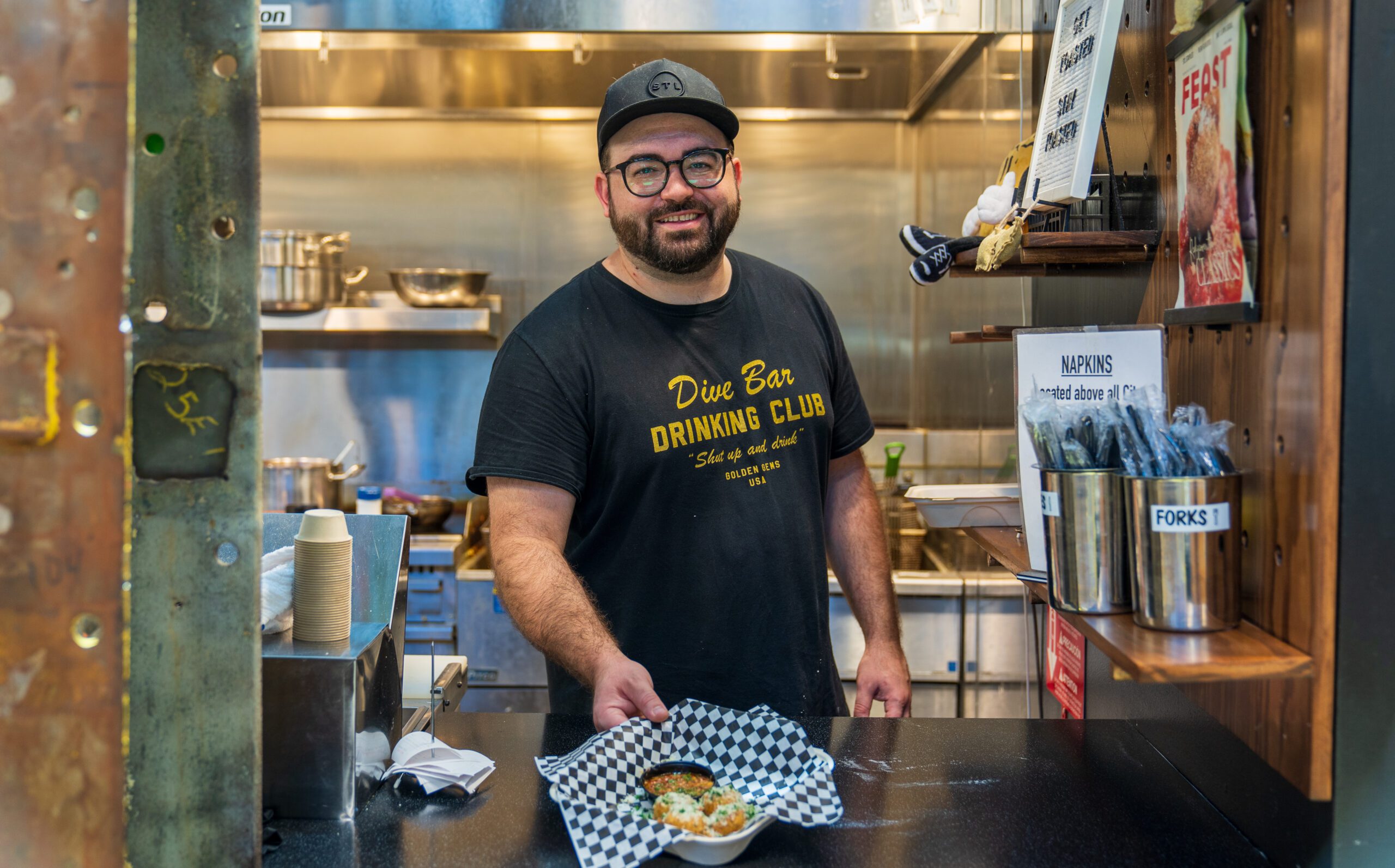 A smiling employee serves food at STL Toasted inside City Foundry STL.