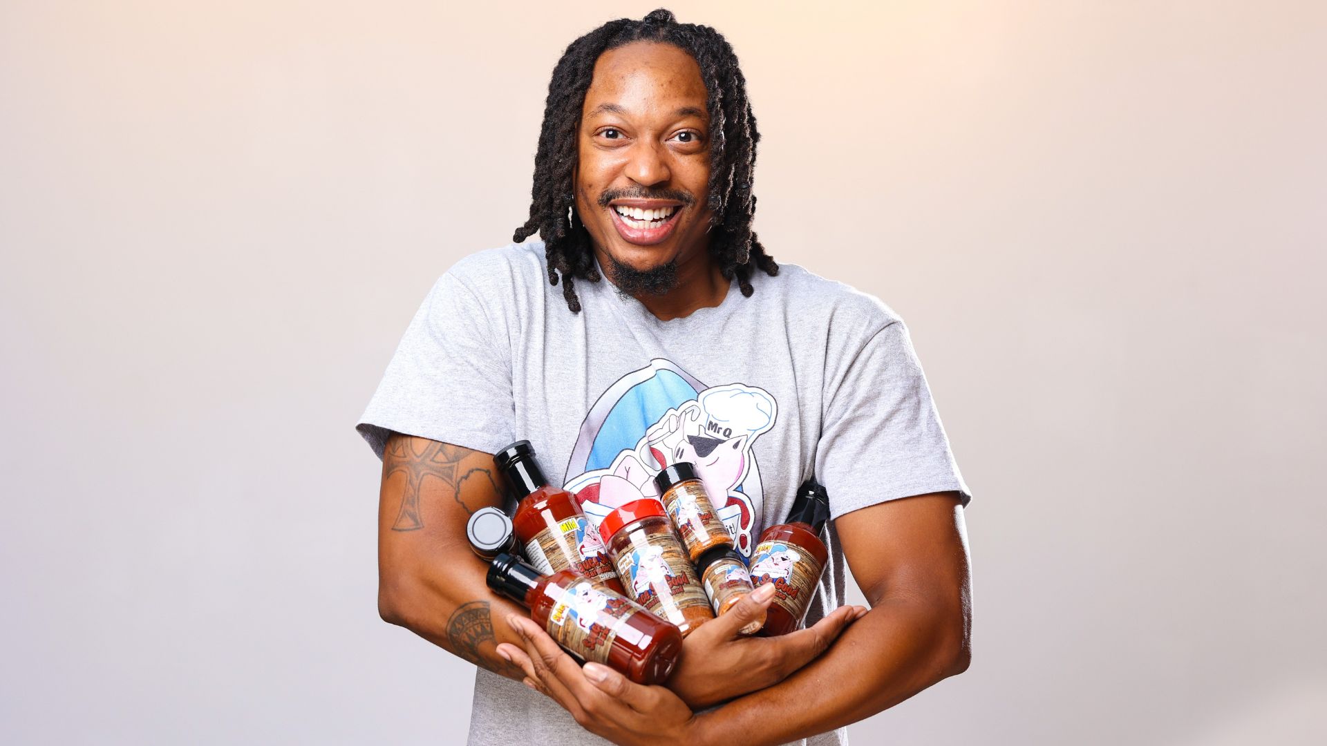 Keyon Watkins, owner of Sauce So Good, holds an armful of products available at Soulard Farmers Market.