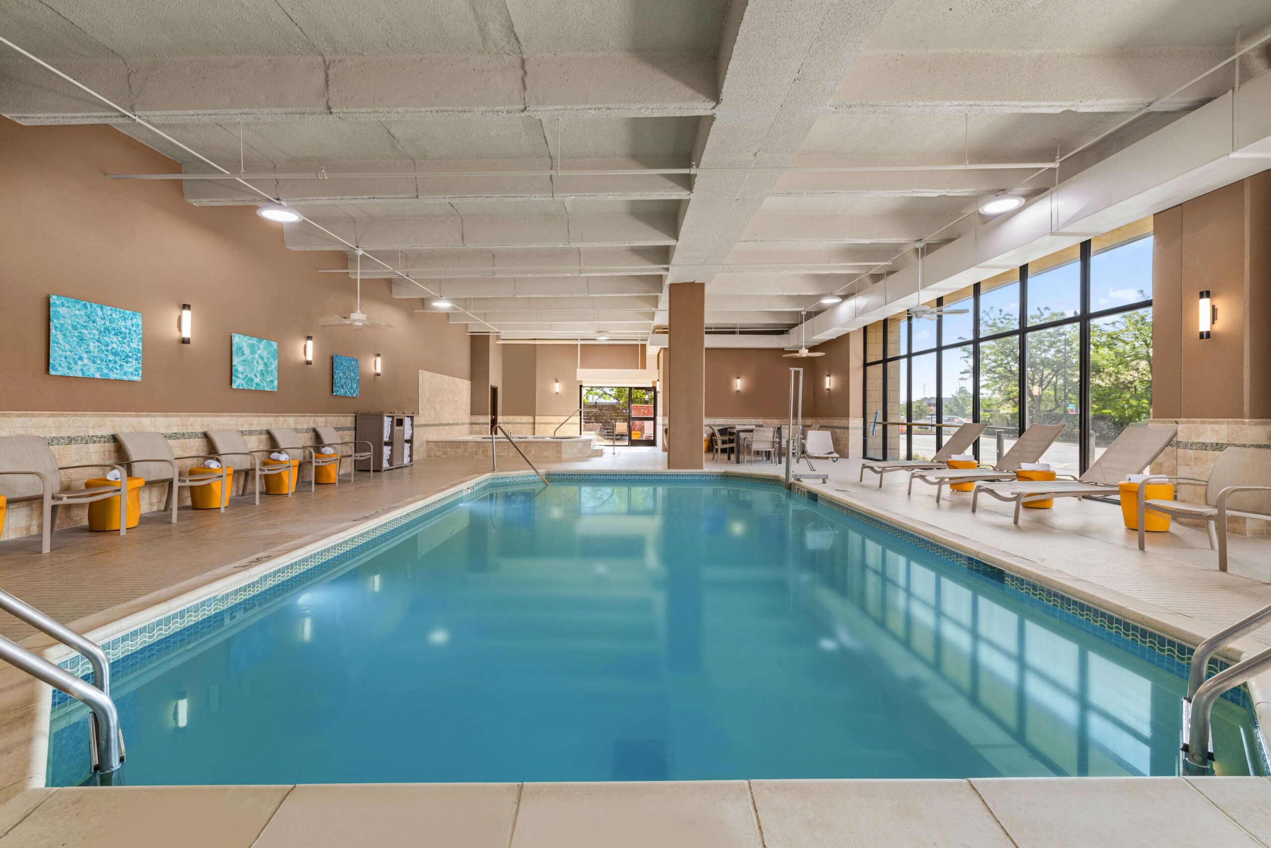 Large indoor swimming pool and relaxing whirlpool surrounded by lounge seating and large windows at Drury Inn & Suites St. Louis Creve Coeur.