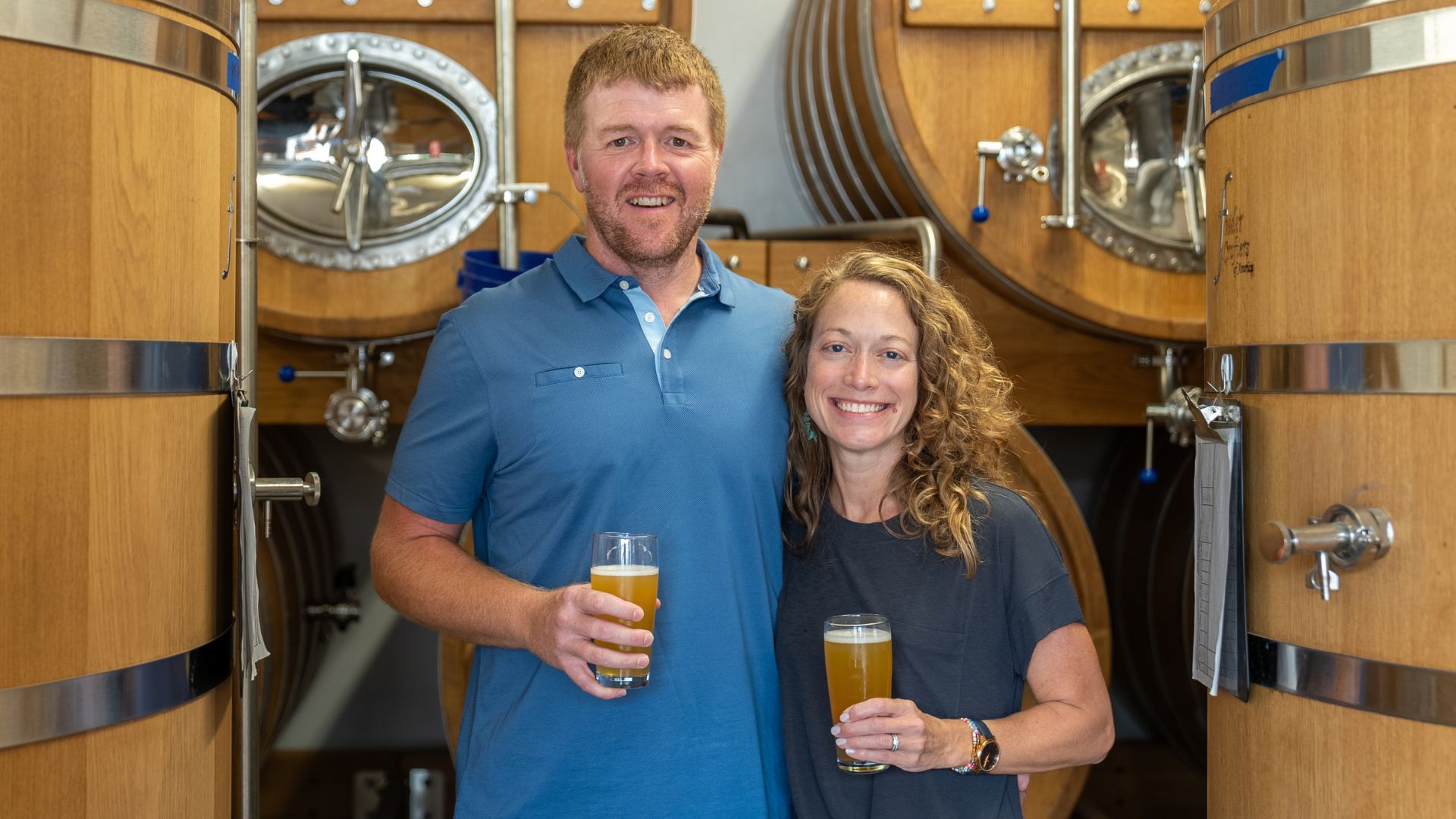 Cory and Karen King pose next to the giant oak barrels where their beer ages.