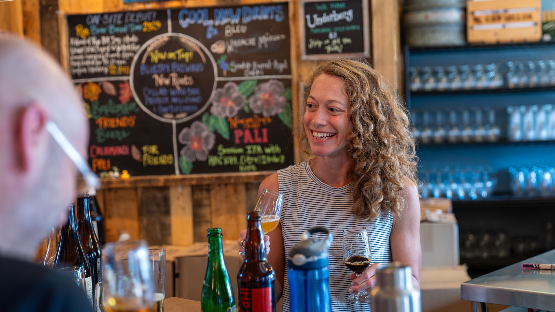 Karen King, co-owner of Side Project Brewing, smiles behind the bar of The Cellar.