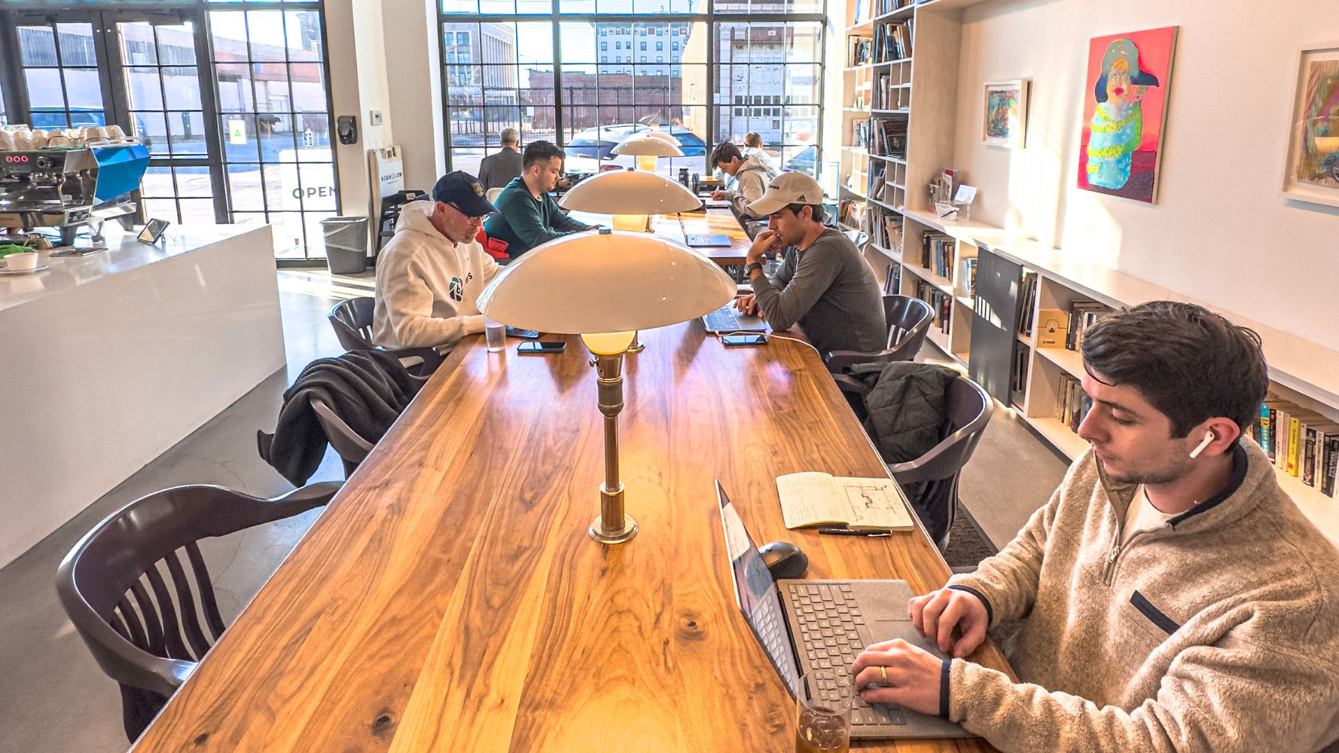 People work, talk and drink coffee at a communal table at High Low in St. Louis.