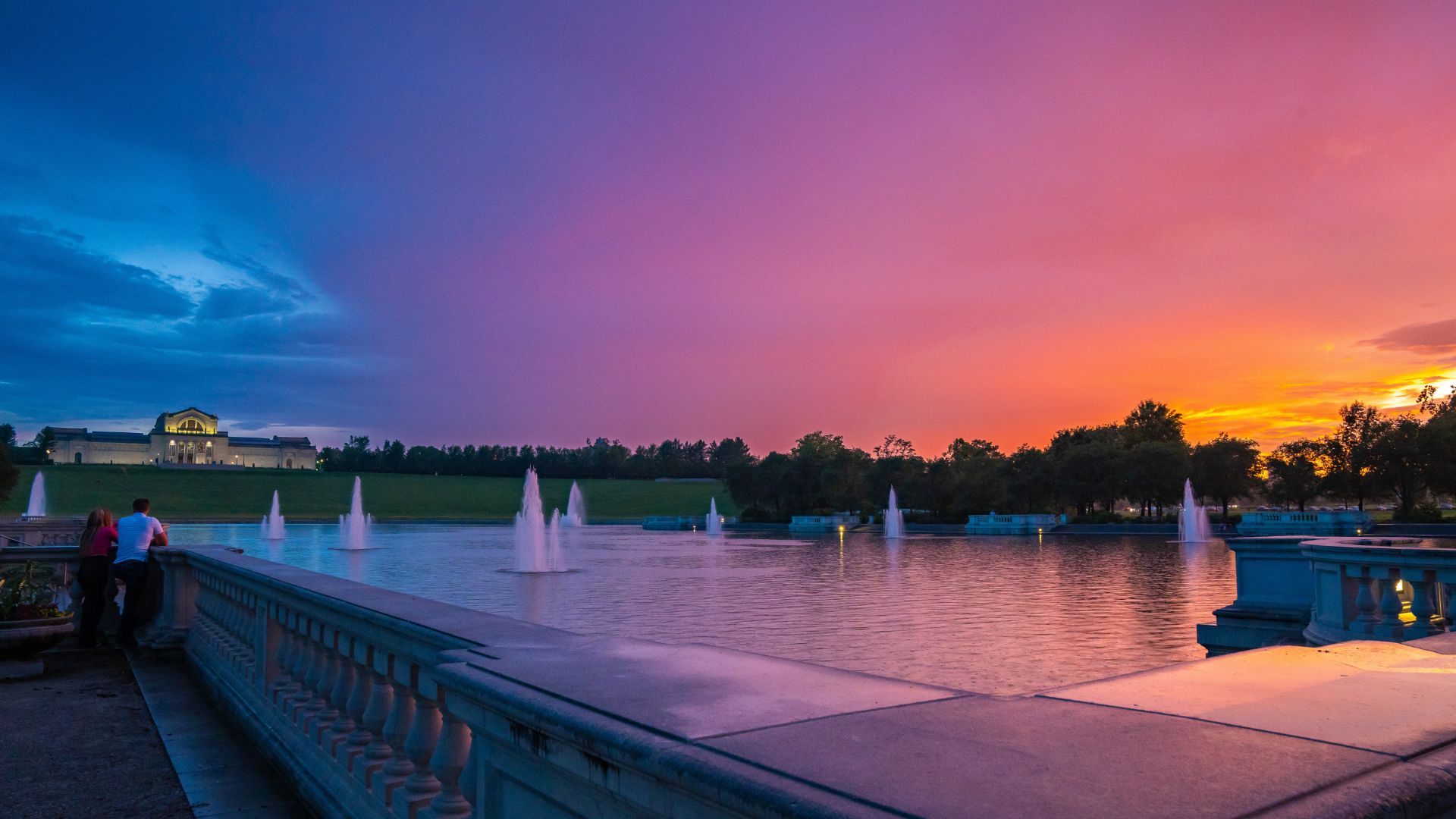 As the sun sets behind the Grand Basin in Forest Park, the sky turns pink and purples.