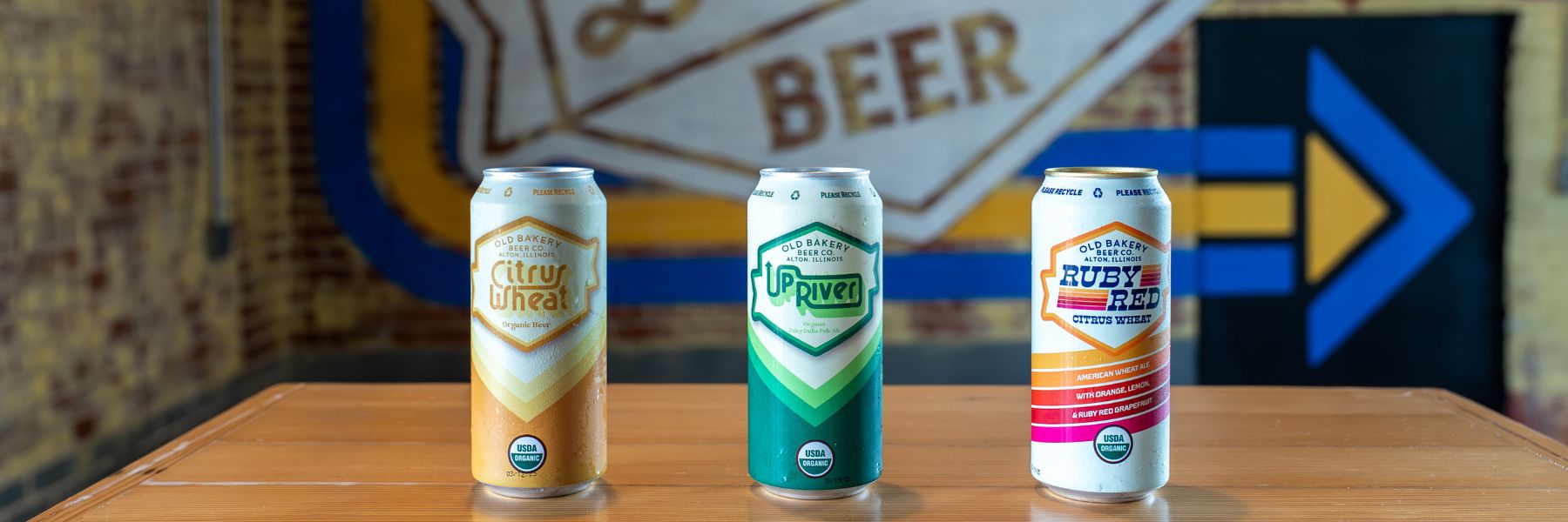 Three cans from Old Bakery Beer Co, including the citrus wheat, up river and ruby red, line a table at the Alton, Illinois, brewery.