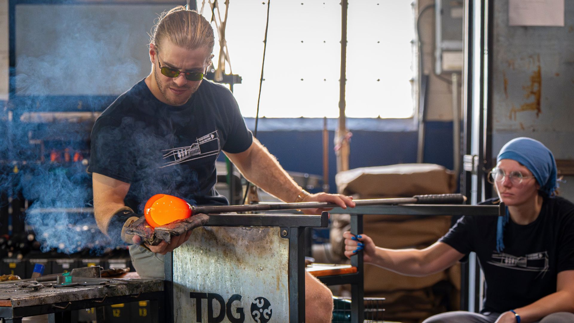 A man and woman practice glassblowing at Third Degree Glass.